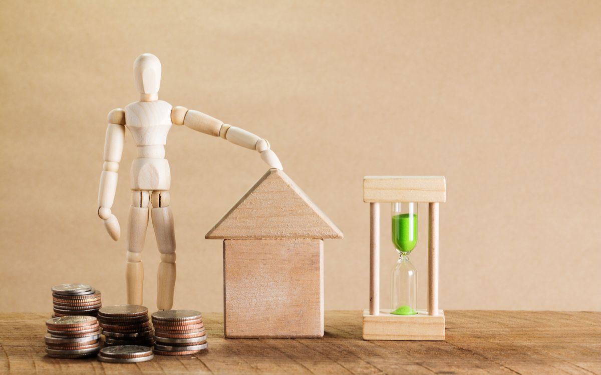 A model house with coins and an hourglass