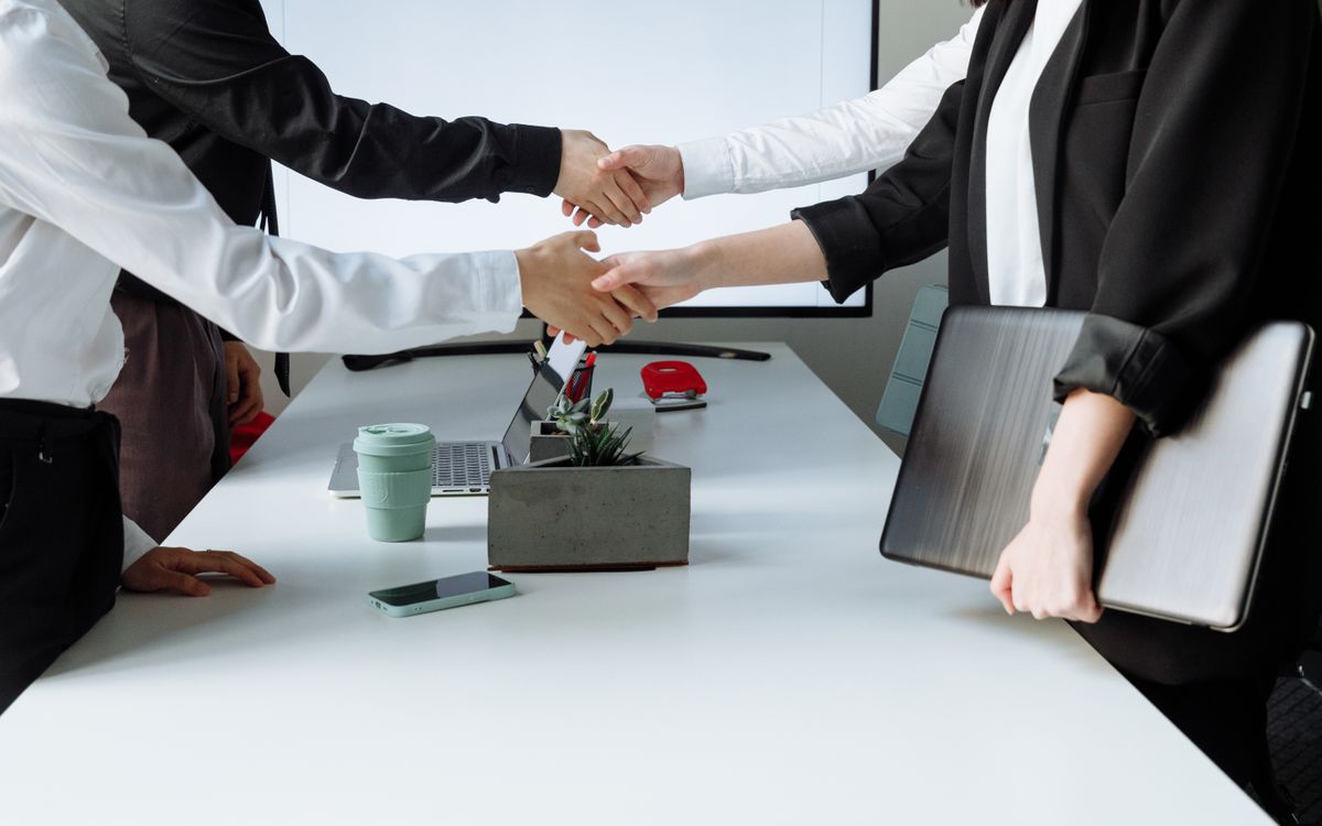Two people shaking hands across a table